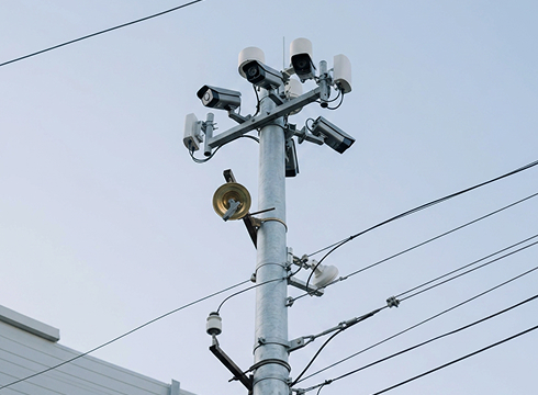 Utility pole with electrical wires and equipment against a clear blue sky, showcasing urban infrastructure.